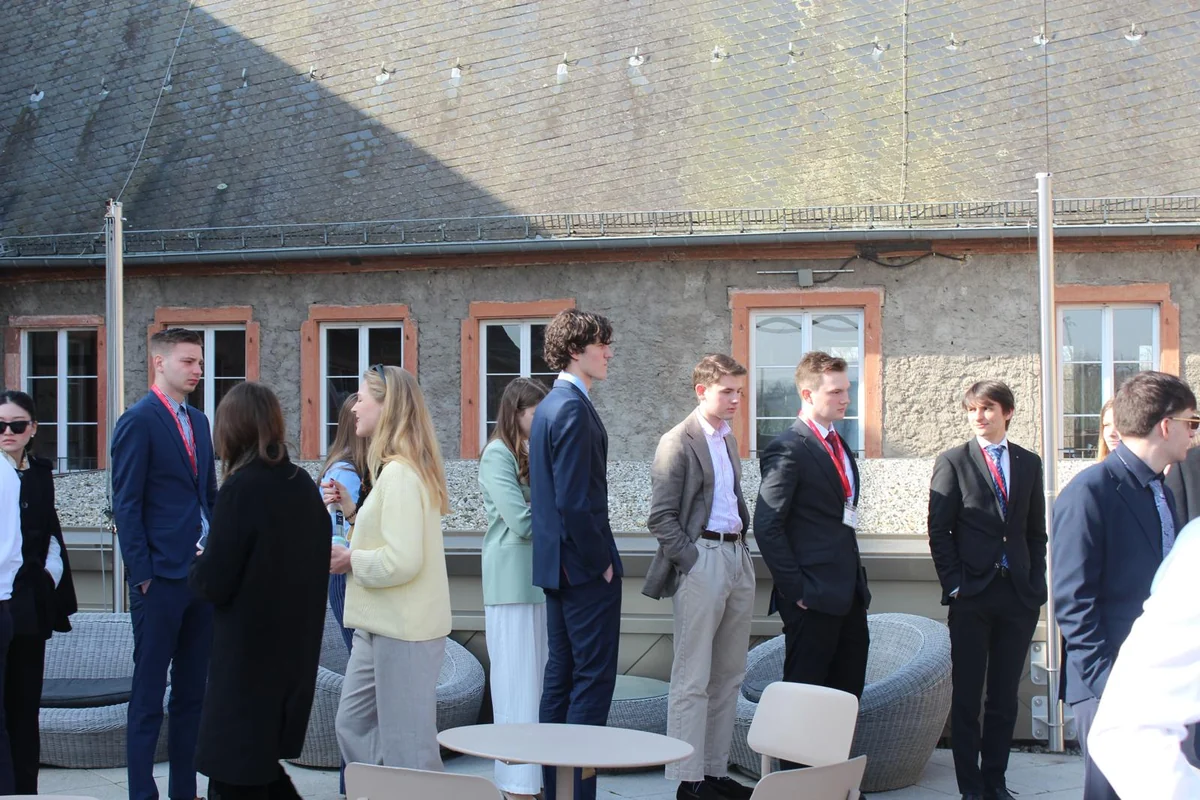 Delegates in suits talking on the sunny roof terrace between sessions